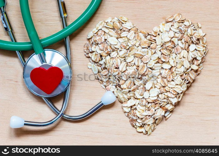 Dieting healthcare concept. Oat cereal heart shaped, stethoscope on wooden surface. Healthy food for lowering cholesterol, protect heart.