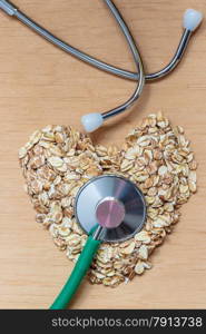 Dieting healthcare concept. Oat cereal heart shaped, stethoscope on wooden surface. Healthy food for lowering cholesterol, protect heart.