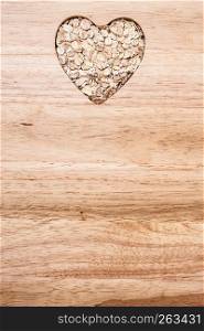 Dieting healthcare concept. Oat cereal oatmeal heart shaped on wooden surface. Healthy food for lowering cholesterol.