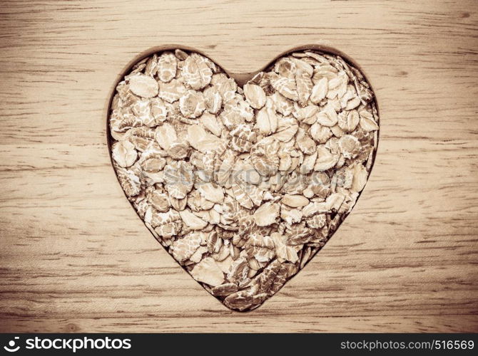 Dieting healthcare concept. Oat cereal oatmeal heart shaped on wooden surface. Healthy food for lowering cholesterol.