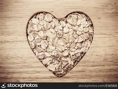 Dieting healthcare concept. Oat cereal oatmeal heart shaped on wooden surface. Healthy food for lowering cholesterol.