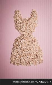 Dieting healthy eating slim down concept. Female dress shape made from oatmeal thin figure on pink