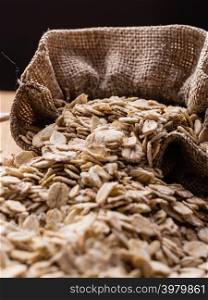 Dieting. Oat cereal in burlap sack on wooden surface. Healthy food for lowering cholesterol, protect heart.