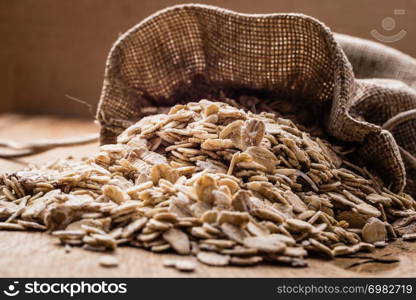 Dieting. Oat cereal in burlap sack on wooden surface. Healthy food for lowering cholesterol, protect heart.