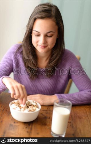 Dieting teenage girl eating healthy cereal with yogurt for breakfast