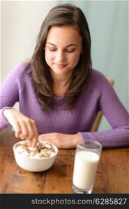 Dieting teenage girl eating healthy cereal with yogurt for breakfast