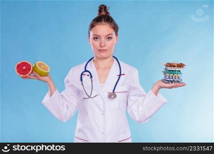 Dietitian nutritionist woman holding diet weight loss tablets pills and grapefruits. Choice between natural and synthetic way of slimming dieting. Health care.. Woman with diet weight loss pills and grapefruits.