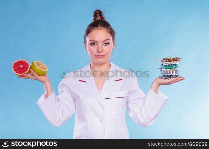 Dietitian nutritionist woman holding diet weight loss tablets pills and grapefruits. Choice between natural and synthetic way of slimming dieting. Health care.. Woman with diet weight loss pills and grapefruits.