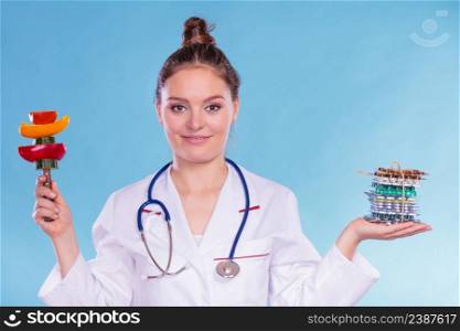 Dietitian nutritionist woman holding diet weight loss tablets pills and vegetables. Choice between natural and synthetic way of slimming dieting. Health care.. Woman with diet weight loss pills and vegetables.