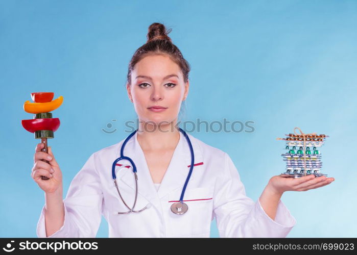 Dietitian nutritionist woman holding diet weight loss tablets pills and vegetables. Choice between natural and synthetic way of slimming dieting. Health care.. Woman with diet weight loss pills and vegetables.