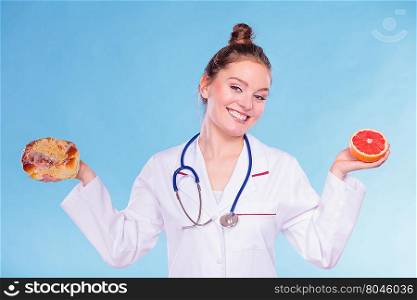 Dietitian with sweet roll bun and grapefruit.. Dietitian nutritionist with sweet roll bun and grapefruit. Woman holding fruit and cake. Junk and healthy food eating nutrition.