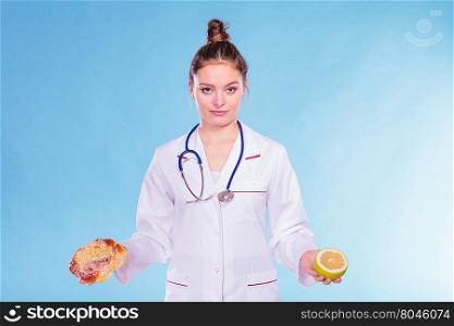 Dietitian with sweet roll bun and grapefruit.. Dietitian nutritionist with sweet roll bun and grapefruit. Woman holding fruit and cake comparing junk and healthy food. Right eating nutrition concept.