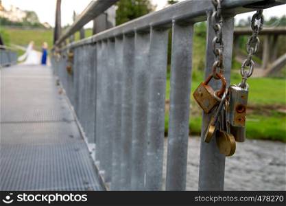Different ages padlocks on the metal bridge in Latvia. Wedding tradition. Rusty locks on the bridge hanging chain.