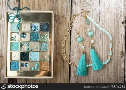 different azure beads and chrystals in box handmade jewelry around old style wooden background. close up