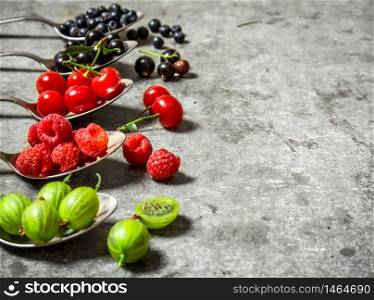 Different berries spoons. On a stone background.. Different berries spoons. On stone background.