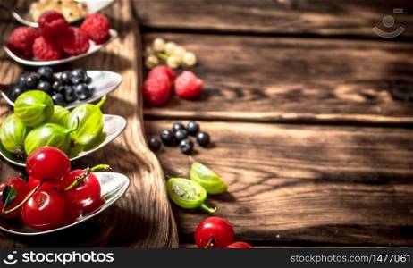 Different berries spoons. On a wooden background.. Different berries spoons. On wooden background.