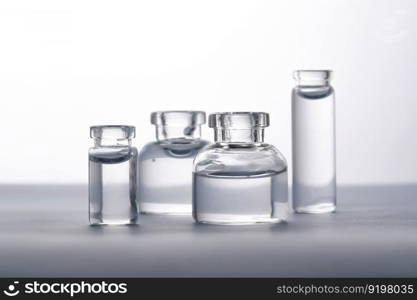 Different bottles of water on a light background. It can fit the theme of cosmetics, glass and freshness.