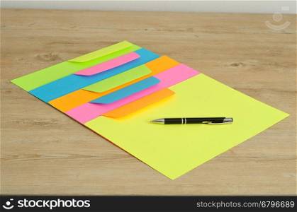 Different color papers and envelopes with a black pen