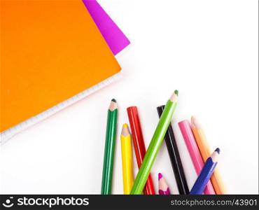 different colored pencils and notebook on white paper