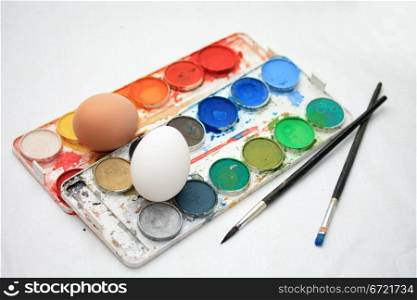 Different colors of paint, brushes and fresh eggs to make traditional easter decorations