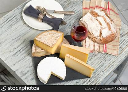 Different french cheeses with a glass of red wine