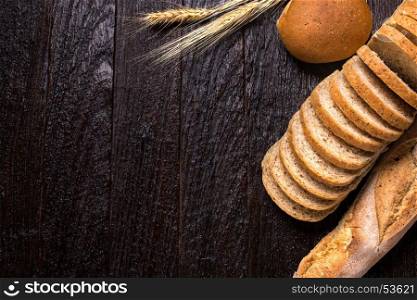 Different fresh bread, on old wooden table and copy space for text, dark tone