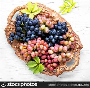 Different grapes on a tray. Bunches of fresh ripe grapes on a wooden retro tray