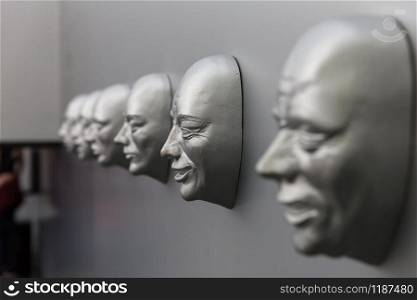 Different human emotions, sculptural mask on the wall. Emotion concept, face models. Different human emotions, sculptural mask