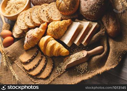 Different kinds of bread with nutrition whole grains on wooden background. Food and bakery in kitchen concept. Delicious breakfast gouemet and meal. Top view angle