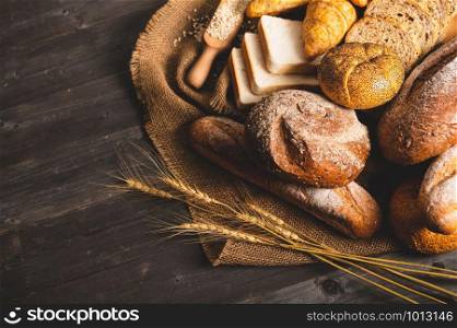Different kinds of bread with nutrition whole grains on wooden background. Food and bakery in kitchen concept. Delicious breakfast gouemet and meal. Top view angle