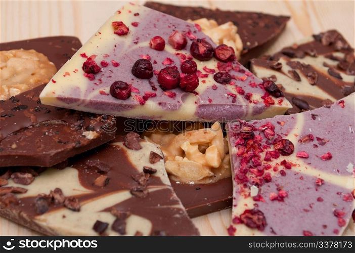 Different Kinds of Broken Chocolate Bars on Wooden Background