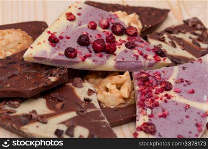 Different Kinds of Broken Chocolate Bars on Wooden Background