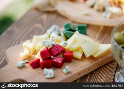 Different kinds of cheese with wine, figs, walnuts, ham, grapes, honey, toast. In a rustic style.. Cheese set on a plate laid out on a beige background. Different types of cheeses: Camembert, Parmesan, blue cheese, olives