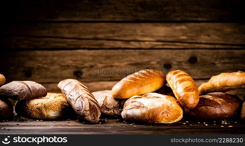 Different kinds of delicious bread. On a wooden background. High quality photo. Different kinds of delicious bread.