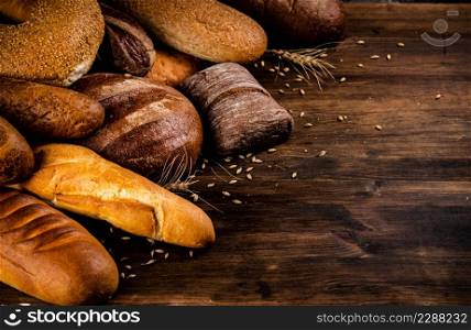 Different kinds of delicious bread. On a wooden background. High quality photo. Different kinds of delicious bread.