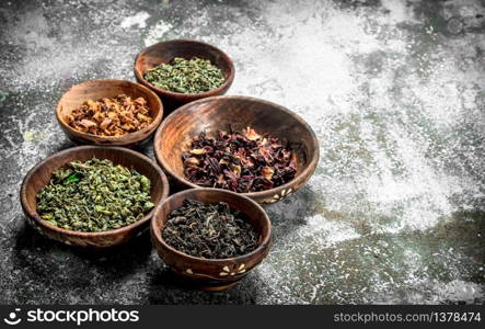 Different kinds of fragrant tea in bowls. On a rustic background.. Different kinds of fragrant tea in bowls.