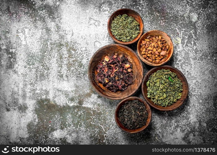 Different kinds of fragrant tea in bowls. On a rustic background.. Different kinds of fragrant tea in bowls.