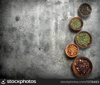 Different kinds of fragrant tea in bowls. On a rustic background.. Different kinds of fragrant tea in bowls.