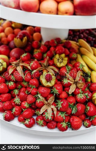 different kinds of fresh fruit on a tray on a banquet. fruit background with with strawberries, bananas, kiwi and peaches.. different kinds of fresh fruit on a tray on a banquet. fruit background with with strawberries, bananas, kiwi and peaches