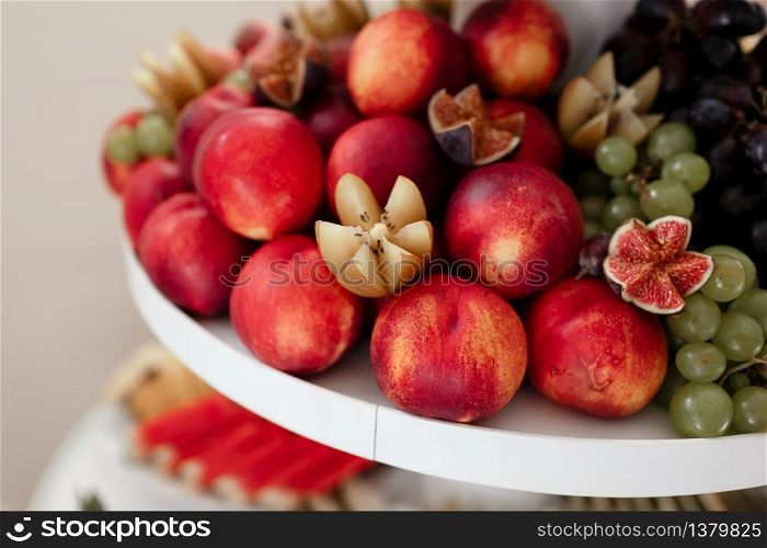 different kinds of fresh fruit on a tray on a banquet. fruit background with peaches, grapes and figs. selective focus.. different kinds of fresh fruit on a tray on a banquet. fruit background with peaches, grapes and figs. selective focus