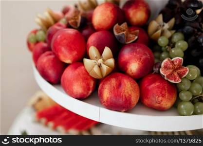 different kinds of fresh fruit on a tray on a banquet. fruit background with peaches, grapes and figs. selective focus.. different kinds of fresh fruit on a tray on a banquet. fruit background with peaches, grapes and figs. selective focus