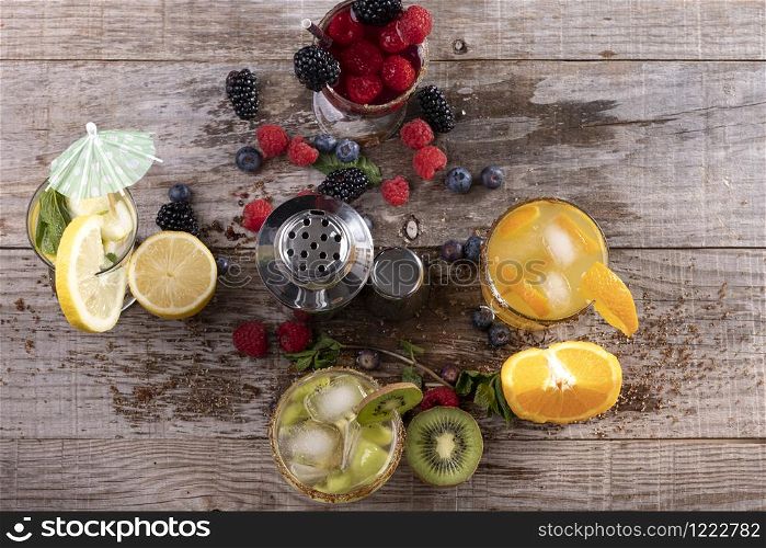 different kinds of fruit juices accompanied by a metal shaker on a wooden base. concept of healthy living