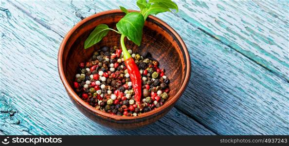 Different kinds of peppercorns.. Black,red and white pepper in clay bowl