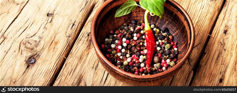 Different kinds of peppercorns.. Black,red and white pepper in clay bowl.Assorted peppercorns