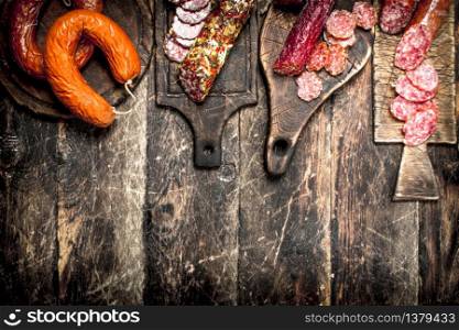 Different kinds of salami on the boards. On a wooden background.. Different kinds of salami on the boards.