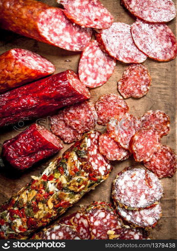 Different kinds of salami on the boards. On a wooden background.. Different kinds of salami on the boards.