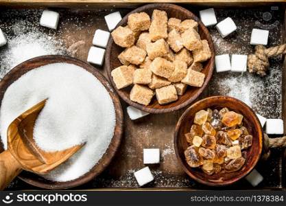 Different kinds of sugar in bowls on a tray. On a rustic background.. Different kinds of sugar in bowls on a tray.