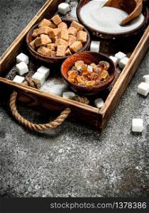 Different kinds of sugar in bowls on a tray. On a rustic background.. Different kinds of sugar in bowls on a tray.