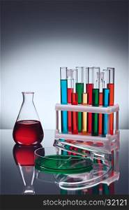 Different laboratory glassware with color liquids on table with reflection