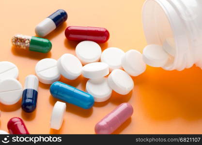 Different multicolored pills and medicine capsules. Different multicolored pills and medicine capsules on orange background